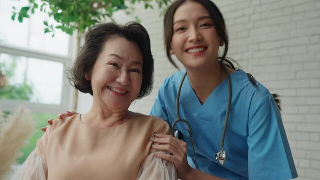 asian young caregiver caring for her elderly patient at senior daycare Handicap patient in a wheelchair at the hospital talking to a friendly nurse and looking cheerful nurse wheeling Senior patient 