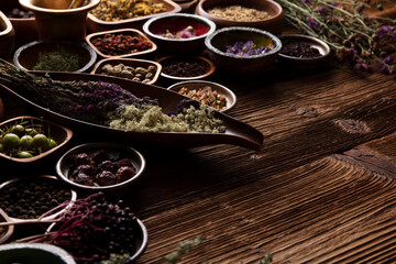 Natural medicine background. Assorted dry herbs in bowls and brass mortar on rustic wooden table.