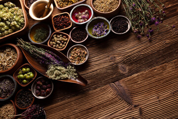  Natural medicine background. Assorted dry herbs in bowls and brass mortar on rustic wooden table.