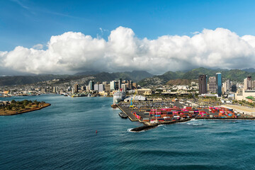 Honolulu city and industrial zone with containers on the lot. Aerial view of industrial zone and tall buildings by the ocean. Clouds over the mountains in background