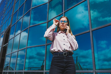 Attractive female blogger holding a modern gadget in her hands, looking thoughtful and daydreaming, young blogger holding a mobile phone, thinking about an idea for posting on social media