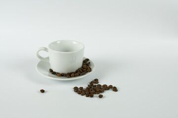 White cup with coffee beans on a white background. The concept is morning rituals.