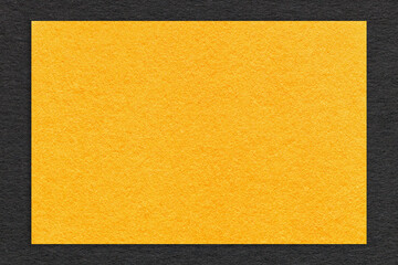 Texture of craft yellow paper background with black border, macro. Structure of cardboard with empty orange frame.