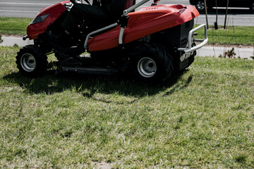 a worker on a lawnmower cuts grass.