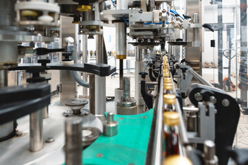 Production line transports closed bottles of yellow alcohol