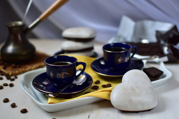 still life with coffee in blue cups, gingerbread with icing and chocolate on the table