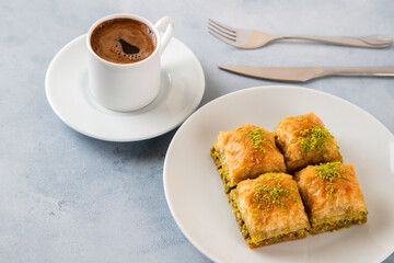 Pistachio baklava on a white plate with Turkish coffee.Traditional Turkish baklava and t coffee on a white background