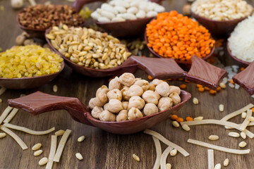 Uncooked dry cereal food group in wooden spoons on wooden surface,harvest concept