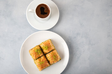 Pistachio baklava on a white plate with Turkish coffee.Traditional Turkish baklava and t coffee on...