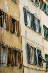 Fototapeta na wymiar Facade of an old house in Florence with weathered wooden window shutters