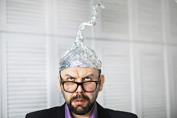 Bearded funny man in a cap of aluminum foil. Concept art phobias.Conspiracy theory. Conspiracy....