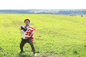Fototapeta premium Man waving American flag standing in grass farm agricultural field , holidays, patriotism, pride, freedom, political parties, immigrant