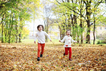 Children for a walk in the autumn park. Leaf fall in the park. Family. Fall. Happiness.