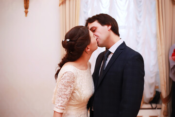 Portrait of emotional lovers of brides indoor.Bride and groom kisses tenderly . Emotional photo of a couple in love on the wedding day.