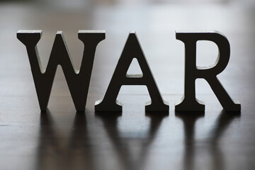 WAR, word written in wooden alphabet letters on blue background. The concept of a terrible war...
