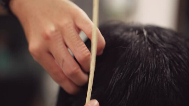 Barber using scissor trimming Asian male customer.Close up.