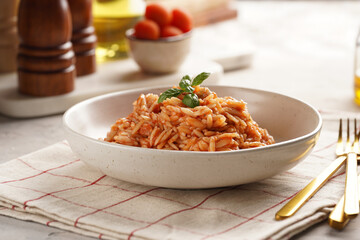 Homemade italian dish pasta risoni with tomato basil sauce in a deep bowl on checkered napkin