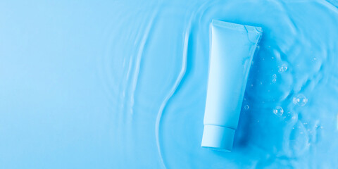 Mock up tube with cosmetic product for moisturizing in water on blue background. Template for design