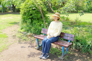 公園のベンチに座る女性 - obrazy, fototapety, plakaty