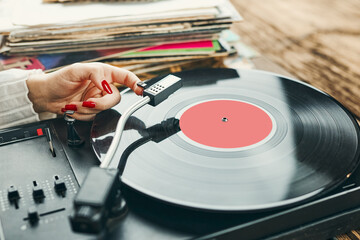 Young woman listening to music from vinyl record player. Playing music on turntable player. Female...