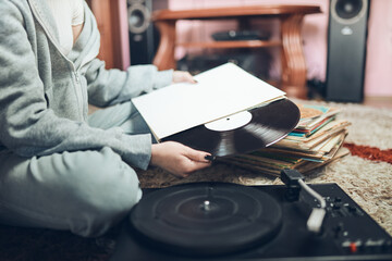 Young woman listening to music from vinyl record player. Retro and vintage music style. Girl...