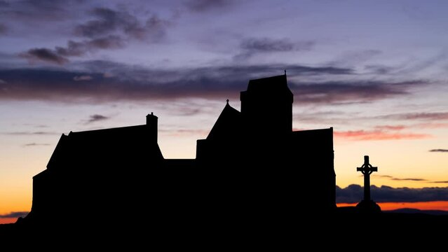 Iona abbey: Time Lapse at Twilight with Colorful Clouds and Silhouette of the most important religious and historic sites in Scotland