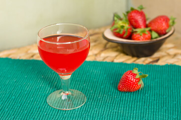 Strawberry liquor on a green runner with strawberries in a bowl on the background