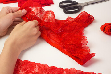 Red lace lingerie, female panties, tailor workplace equipment fabric, thread. Handmade underwear workshop