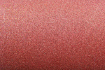 Sandpaper texture background where you can see the red-brown sand grain pattern on the sandpaper, suitable as a background for inserting text.