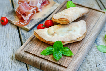 Home made italian calzone pizza with  prosciutto  tomatoes, mozzarella and parmesan cheese and fresh basil 