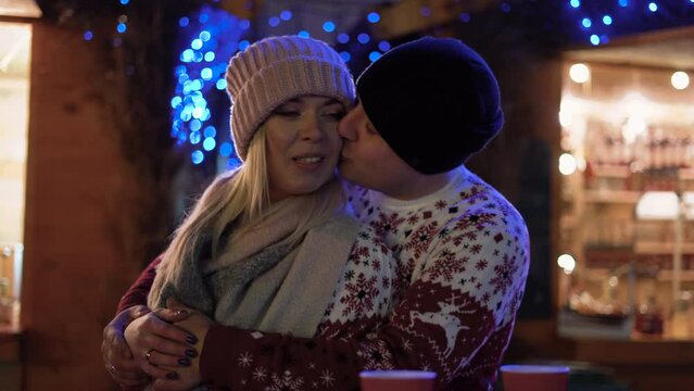 Young romantic couple having fun and kissing outdoors in winter Christmas. woman and man lovers hug and kiss on Valentine's Day.