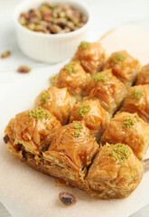 Delicious sweet baklava with pistachios on parchment paper, closeup