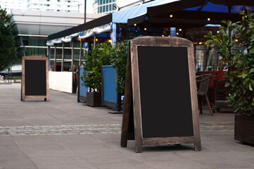 Blank wooden sandwich board near outdoor cafe. Mockup for design