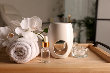 Plakat Aroma lamp, bottle of oil, rolled towel and candles on wooden tray indoors