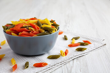 Durum Wheat Semolina Pasta with Tomato and Spinach in a Bowl, side view. Tri-color Penne Pasta. Copy space.