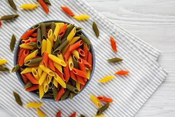 Durum Wheat Semolina Pasta with Tomato and Spinach in a Bowl, top view. Tri-color Penne Pasta. Flat lay, overhead, from above. Copy space.