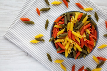 Durum Wheat Semolina Pasta with Tomato and Spinach in a Bowl, top view. Tri-color Penne Pasta. Flat lay, overhead, from above. Copy space.