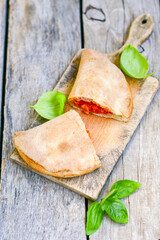 Home made italian calzone pizza with  tomatoes, mozzarella and parmesan cheese and fresh basil 