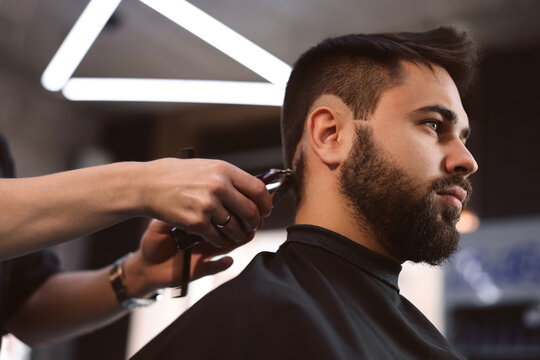 Professional hairdresser working with client in barbershop