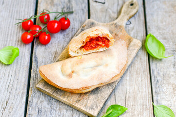 Home made italian calzone pizza with  tomatoes,  prosciutto mozzarella and parmesan cheese and fresh basil 