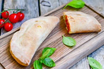 Home made italian calzone pizza with  tomatoes,  prosciutto mozzarella and parmesan cheese and fresh basil 