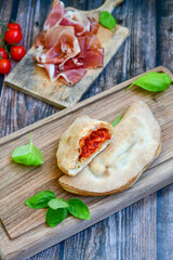 Fototapeta na wymiar Home made italian calzone pizza with tomatoes, mozzarella and parmesan cheese and fresh basil 