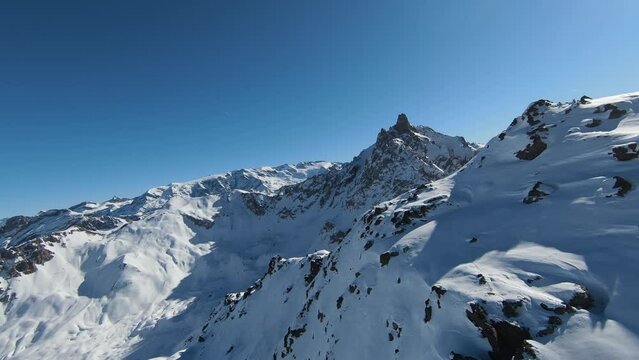 Aerial view sport FPV drone raising up top of mount. Beautiful peaks of the alps covered with snow cover