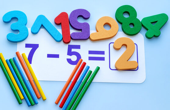 wooden numbers and sticks for counting on blue background,chaotic arrangement.back to school,learning concept.one minus operation and rezult.eco educational toys 