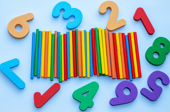 wooden numbers and sticks for counting on blue background,chaotic arrangement.back to school,learning concept.one minus operation and rezult.eco educational toys 