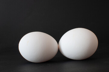 Close up detail view of white raw chicken eggs. Isolated on dark background, selective focus.