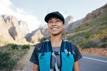 Portrait of a beautiful female hiker in cap. Woman in hiking attire staning in valley.