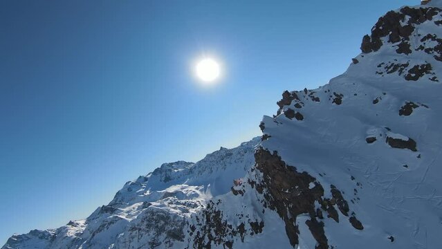 Aerial view sport FPV drone raising up top of mount. Beautiful peaks of the alps covered with snow cover
