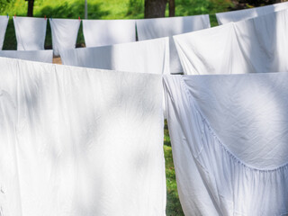 fresh white laundry hanging on a washing rope outdoor in a summer camp in a forest, close up photo