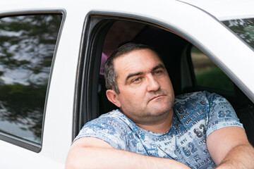 Portrait of a 45-year-old man in a car. A passenger looks out the car window